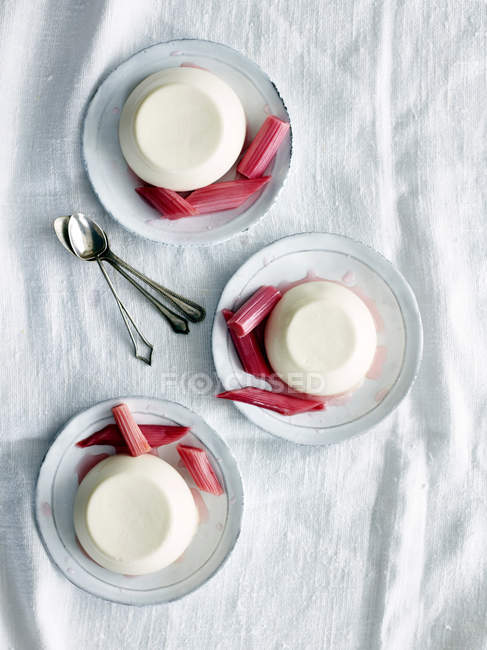 Top view of panna cotta desserts with rhubarb on saucers — Stock Photo