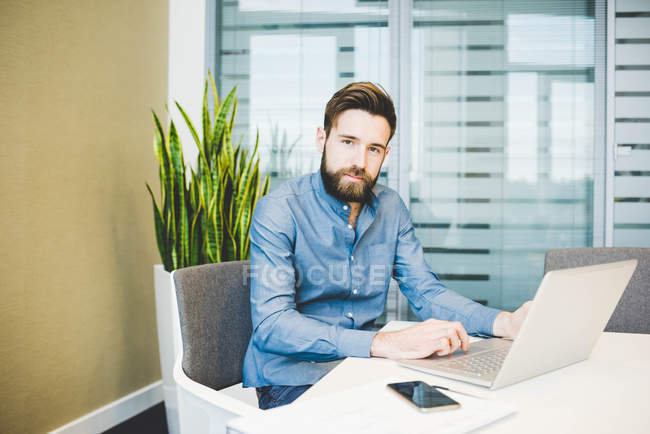 Portrait of young male designer working on laptop in office — Stock Photo