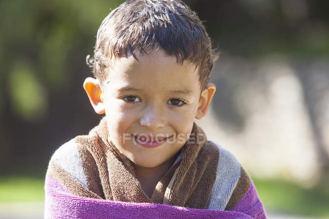 Ritratto di ragazzo con capelli bagnati avvolto in asciugamano in giardino — Foto stock