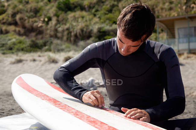 Jovem adulto surfista do sexo masculino encerando bordo — Fotografia de Stock