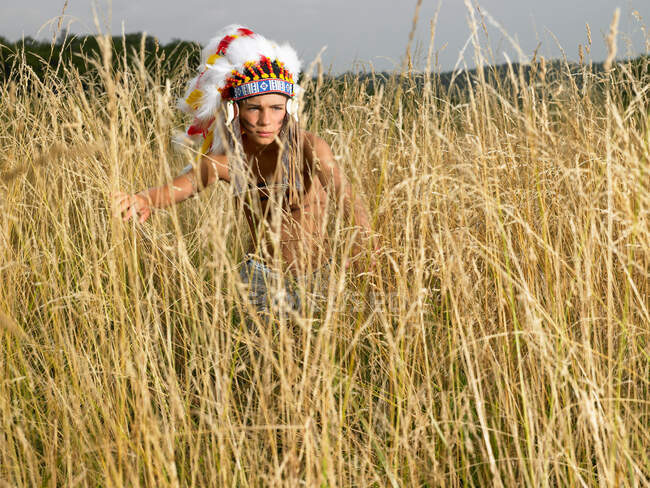 Мальчик, одетый как североамериканский индеец в траве — стоковое фото