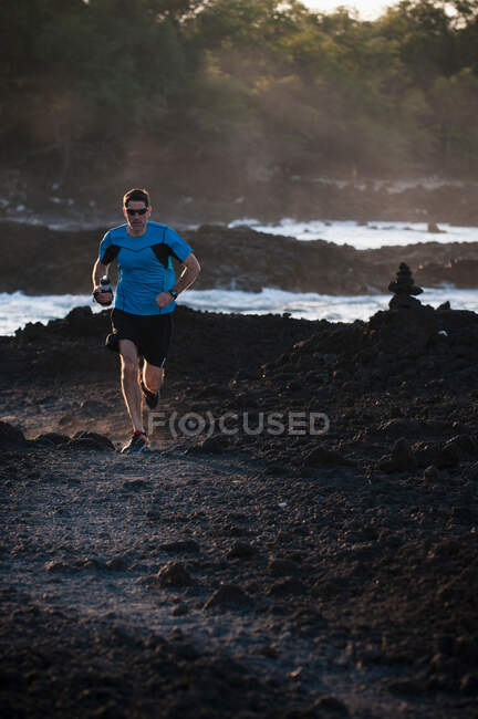 Mann läuft an felsigem Strand — Stockfoto