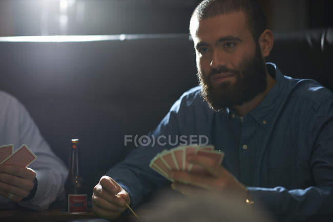 Male friends playing card game at traditional uk pub — Stock Photo