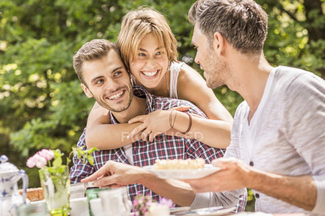 Gruppe von Freunden genießt Gartenparty, junge Frau umarmt jungen Mann — Stockfoto
