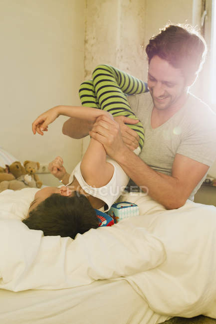Père et petit fils jouent à se battre sur le lit — Photo de stock