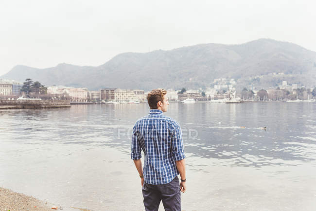 Joven mirando desde la orilla del lago, Lago de Como, Italia - foto de stock