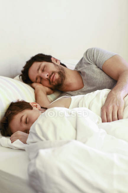 Vater und kleiner Sohn schlafen zu Hause im Bett — Stockfoto
