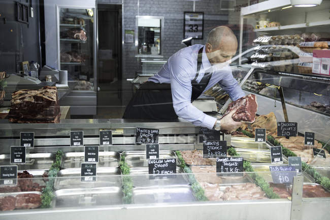 Butcher preparing window display in butcher's shop — Stock Photo
