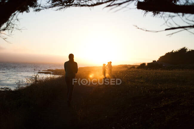 Familie spaziert bei Sonnenuntergang an der Küste entlang — Stockfoto
