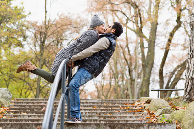 Coppia baciare oltre parco ringhiera — Foto stock