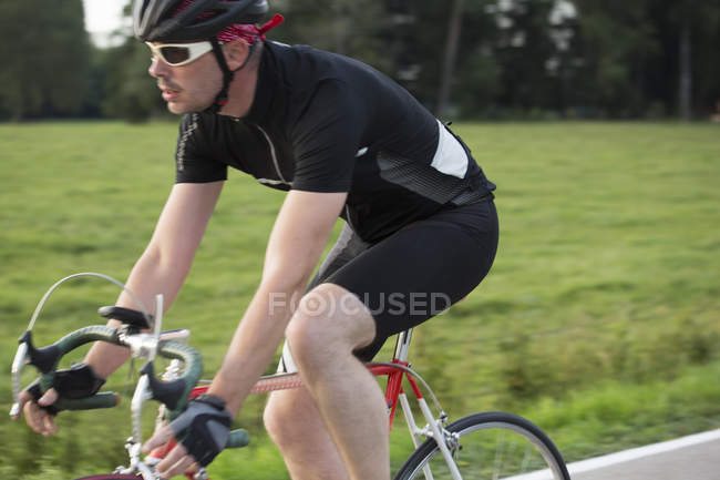 Close up of mature male cycling on country road — Stock Photo