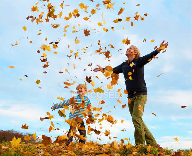 Отец и сын играют осенними листьями — стоковое фото