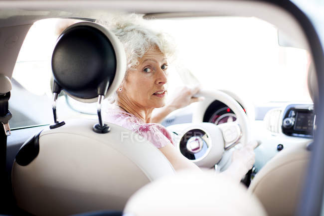 Porträt einer reifen Frau, die im Auto über ihre Schulter schaut — Stockfoto