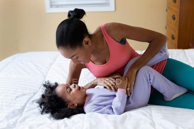 Mother tickling daughter on bed — Stock Photo
