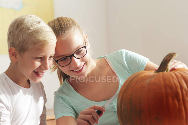 Teenage girl and little boy preparing to carving pumpkin for Halloween — Stock Photo