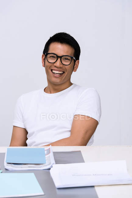 Молодий чоловік сидить за столом з паперовою роботою — стокове фото
