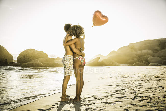 Пара с шаром в форме сердца на пляже — стоковое фото