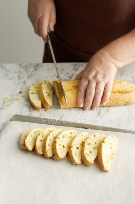 Женщина нарезает хлеб с орехами на кухонном столе — стоковое фото