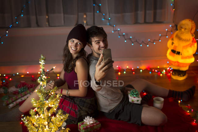 Молодая пара делает селфи в гостиной на Рождество — стоковое фото