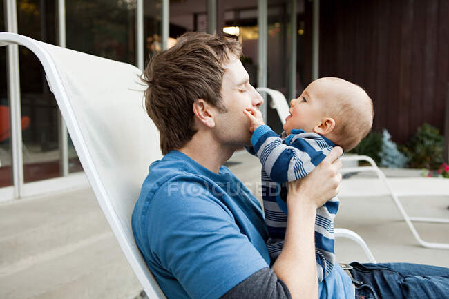 Vater mit Baby auf Liegestuhl sitzend — Stockfoto