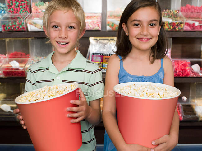 Dos niños sosteniendo tinas de palomitas de maíz - foto de stock