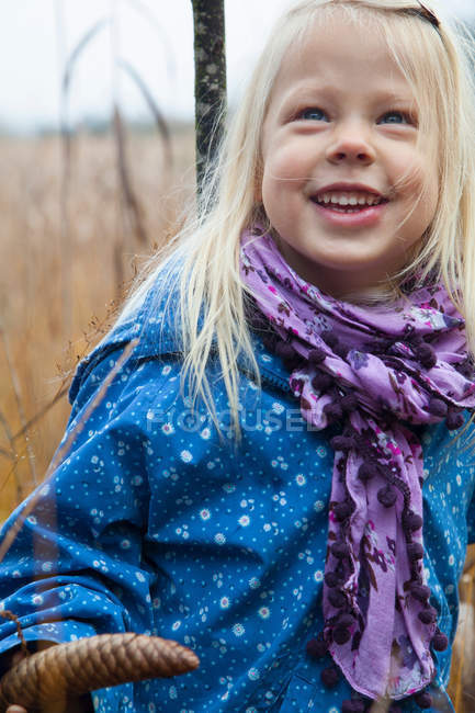 Sonriente chica de pie en la hierba alta - foto de stock