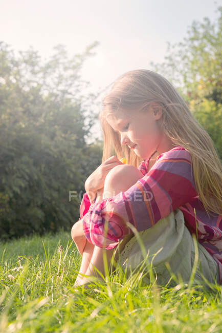 Girl holding buttercup in field during summer — Stock Photo