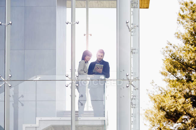 Uomo e donna d'affari che utilizzano tablet digitale sul balcone — Foto stock