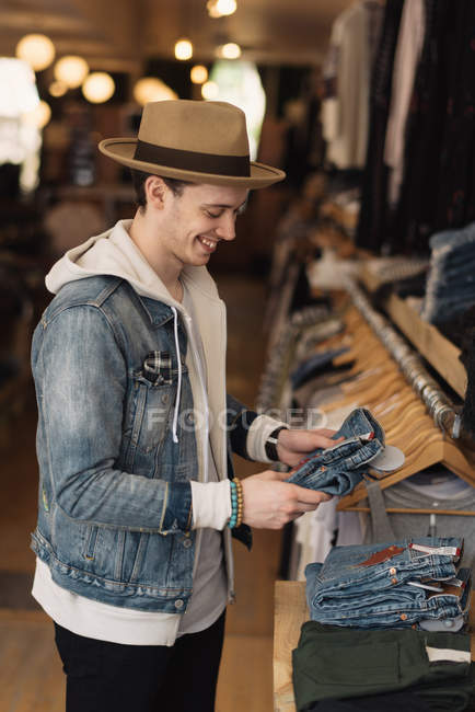 Молодой человек смотрит на одежду в магазине одежды — стоковое фото