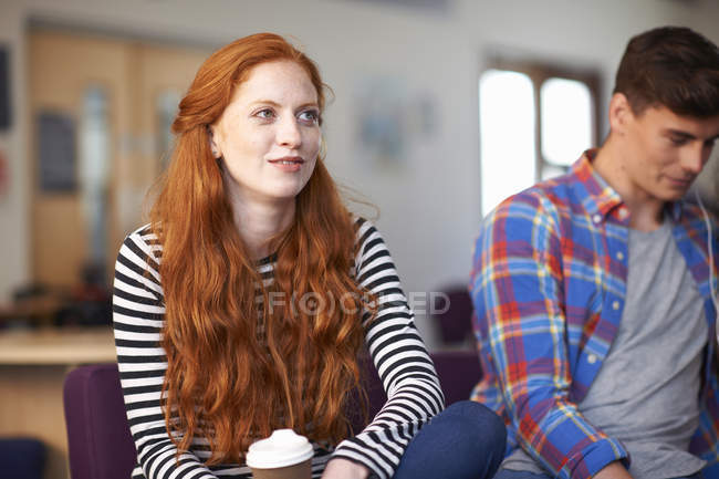 Молода студентка коледжу сидить з кавою в загальній кімнаті — стокове фото