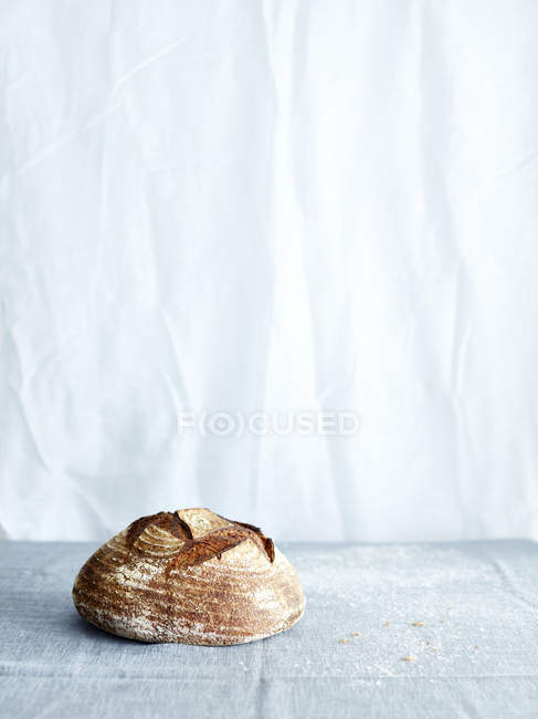 Sourdough bread loaf on gray tablecloth — Stock Photo
