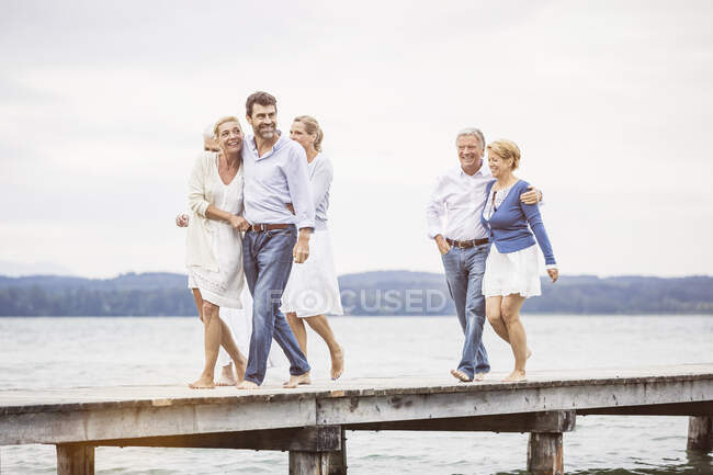 Group of friends standing walking along pier — Stock Photo