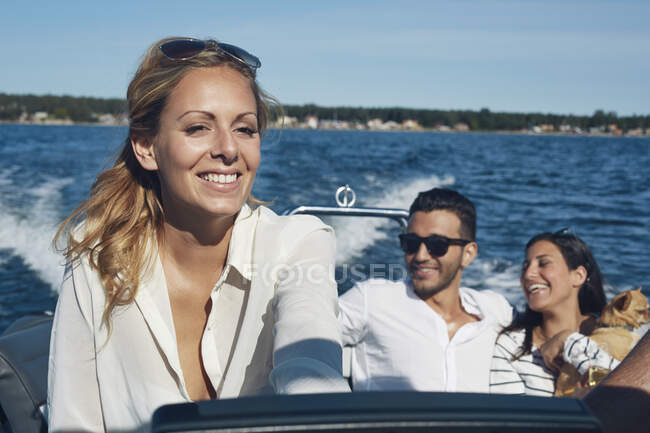 Молодая женщина руля лодки с друзьями в фоновом режиме, Gavle, Швеция — стоковое фото