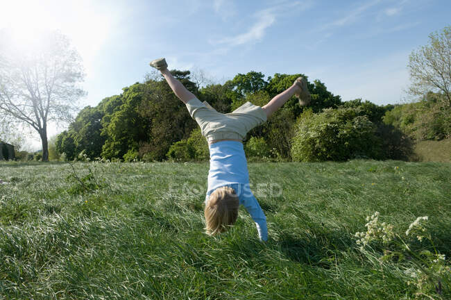 Garçon faisant handstand dans le champ — Photo de stock