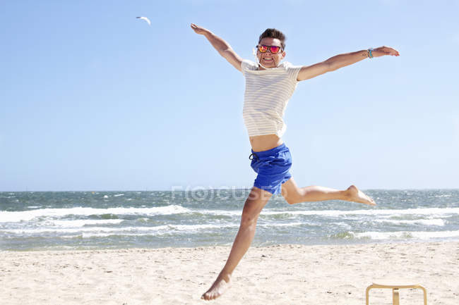 Joven saltando en el aire en la playa, Port Melbourne, Melbourne, Australia - foto de stock