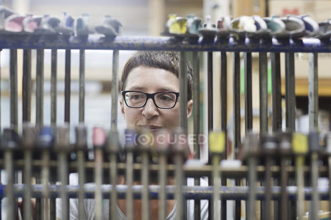 View through hanging clamp tools of woman in workshop — Stock Photo