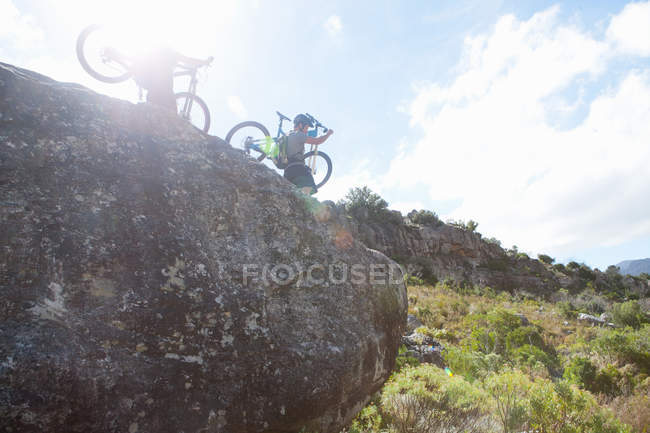 Young couple carrying mountain bikes down from rocks — Stock Photo