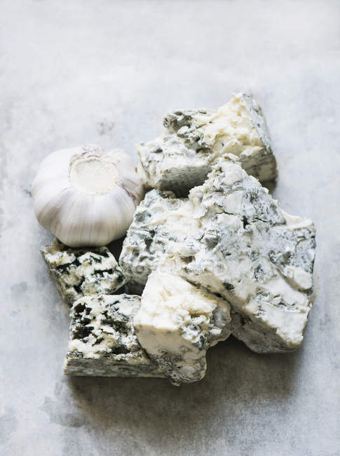 Primer plano de queso azul con ajo en la mesa - foto de stock