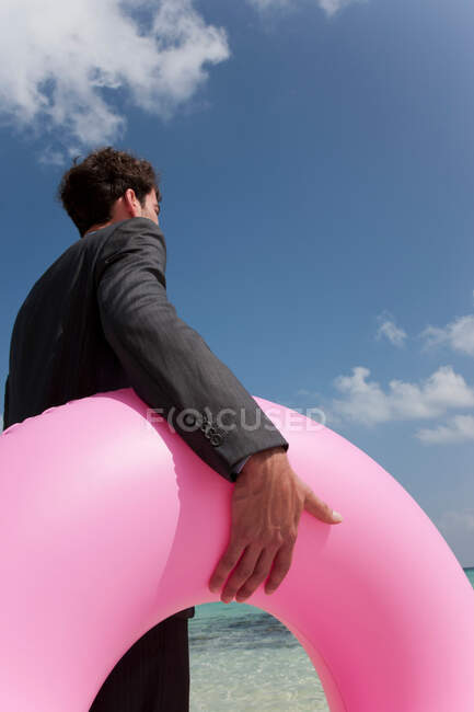 Homme d'affaires portant une chambre à air sur la plage — Photo de stock