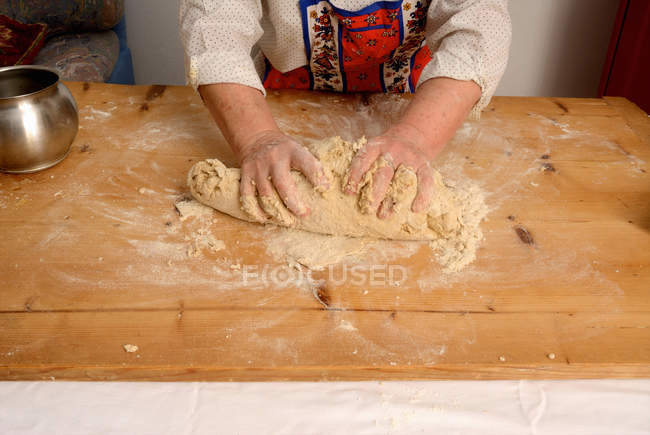 Image recadrée de femme âgée pétrissant la pâte sur la planche à découper — Photo de stock