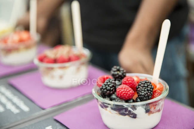 Row of fruit salad portions with berries and yogurt — Stock Photo