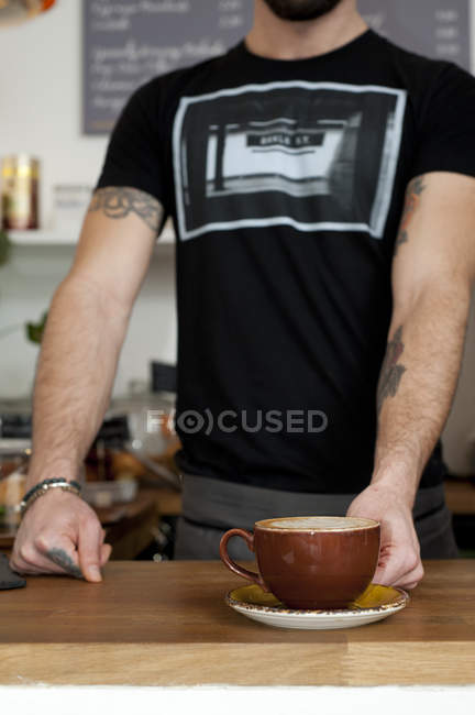 Cortado tiro de camarero de café que sirve taza de café fresco - foto de stock