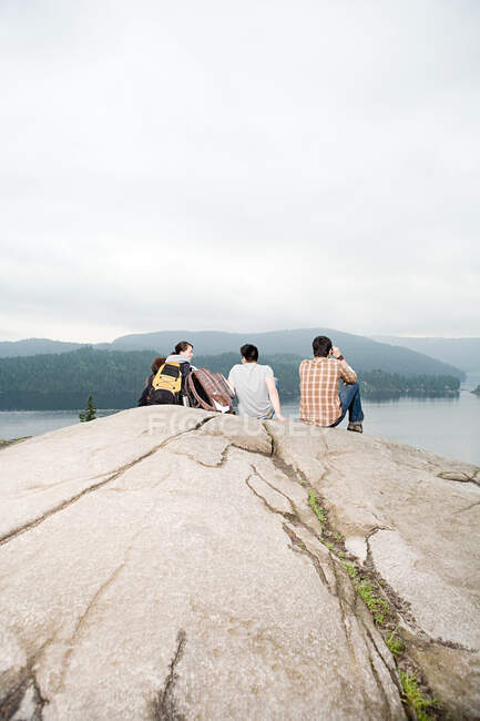 Gente en la roca junto a un lago - foto de stock