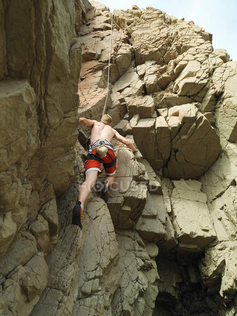 Scalatore scalando ripida parete rocciosa — Foto stock