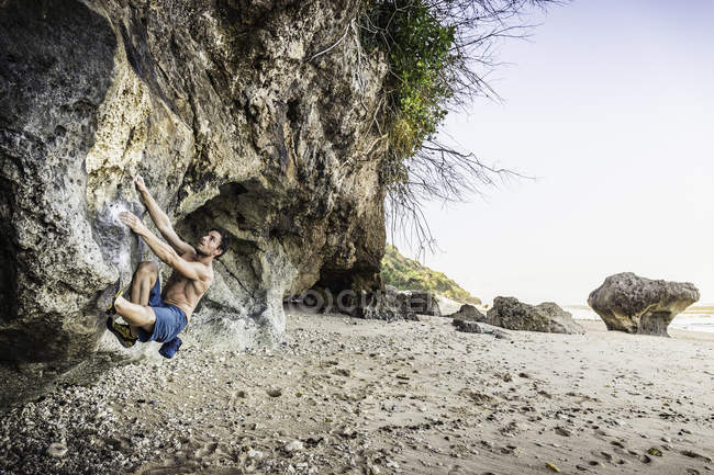 Maschio arrampicatore free climbing parete di roccia sulla spiaggia di Pandawa, Bali, Indonesia — Foto stock