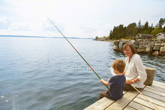 Sorridente nonna guardando ragazzo di pesca — Foto stock