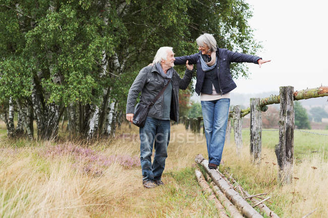 Seniorenpaar balanciert auf Baumstämmen — Stockfoto