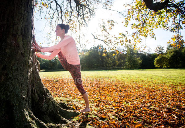 Woman doing yoga in park on autumn day — Stock Photo