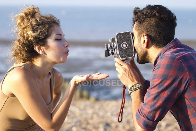 Hombre joven filmando mujer con cámara vintage - foto de stock
