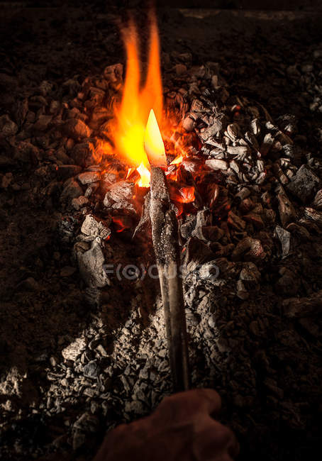 Blacksmith holding metal knife in furnace — Stock Photo
